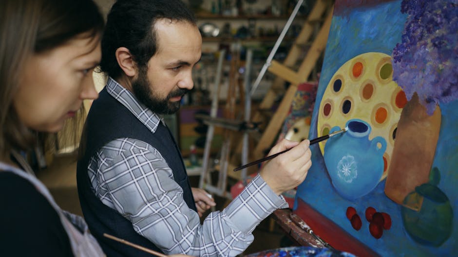 Two artists discussing painting techniques in an art studio, focusing on a colorful canvas.