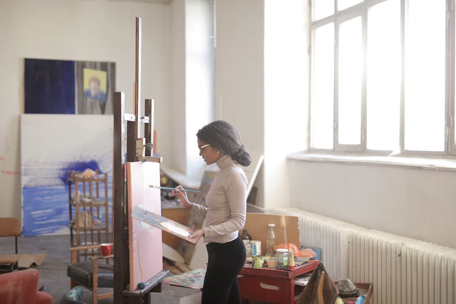 A focused artist paints on canvas in a sunlit studio, embodying creativity and expression.